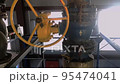 An old valve with a yellow round steering wheel on a heating pipe in a boiler room. 95474041