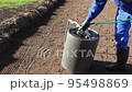 Worker man with hose filling soil ground hardener roller with water. Static shot 95498869