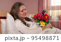 young woman enjoying bouquet of colorful tulips in bedroom. 4 95498871