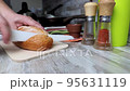 Cutting fresh bread into pieces in kitchen interior with a special knife 95631119
