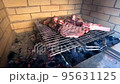 Beef steaks on the bone are grilled on a grate over coals 95631125