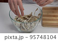 Close-up of female hands mixing mushrooms in a cooking bowl 95748104