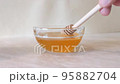 Man dips a wooden stick in honey and it pours, drips into a glass bowl. Useful natural honey. Overall plan. 95882704
