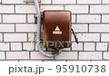 An old, rusty electric inlet panel with a wire in a plastic protection included in a brick house. 95910738
