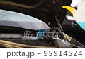 Close-up detail of driver or mechanic hand in gloves pouring blue antifreeze liquid for winter car windshield screen washing with bootle watering can. Car seasonal service and maintenance concept 95914524