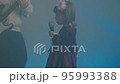 Little girl on stage in vintage dress, she sings into microphone and dances, her father plays an electric guitar. Color music is shining and smoke is billowing. Family time, creativity and hobbies 95993388