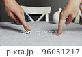 Two people play soccer with fingers using a small toy ball on the kitchen table. 96031217