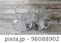 Pouring hot water in glasses of green tea on a wooden table directly above view 96088902