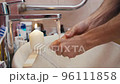 Man washes hands with water from the tap, which is heated by a lit candle 96111858