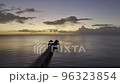 A Wooden Pier with a Sunset on the Background with Orange Sky a Top Drone Shot Dollying from right to left 96323854