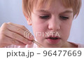 Close-up of the child artist's face. A small talented man diligently paints a picture with a brush. The face expresses emotions. Focus and seriousness. Beautiful redhead child with a short haircut 96477669