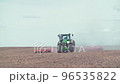Modern red tractor plows an agricultural field 96535822