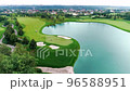 Drone flies over a large golf course with lakes on a clear summer day. 96588951