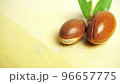 Argan nuts with green leaves motion on wooden background.  96657775