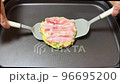 ホットプレートの上でお好み焼きをひっくり返す 96695200