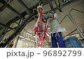 Butcher is using sharp knife and cutting the raw pig on two halves 96892799