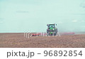Modern red tractor plows an agricultural field 96892854