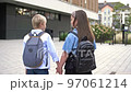 School friendship. A boy and a girl, primary school students, walk out of the school building holding hands. Back view. 97061214