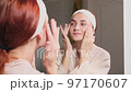 Woman doing her daily skincare routine in bathroom  97170607