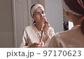 Beautiful woman looking at mirror and removing makeup 97170623