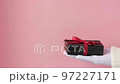 Hand in white glove holds out a black gift box in the palm of his hand 97227171