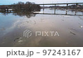 Automobile bridge across a gloomy river stream with floating ice floes. 97243167
