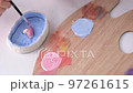 A child makes a craft for Valentine's Day. A close-up of the brush paints the heart pink. Gift. A pink heart on a blue background. 97261615