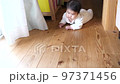 A baby crawling inside a house with a wooden floor 97371456