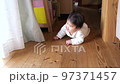 A baby crawling inside a house with a wooden floor 97371457