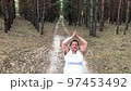 A fat woman is engaged in breathing exercises in a pine forest. Mental health. Gray hair 97453492