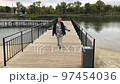 A positive fat woman dances on the bridge of the river in the fall. Mental health.  97454036