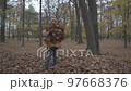 The boy throws up a huge armful of autumn leaves and falls with pleasure. Slowmo 97668376