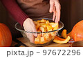 a female chef mixes pieces of sliced pumpkin in a large glass bowl in the kitchen. 97672296