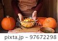 a female chef mixes pieces of sliced pumpkin in a large glass bowl in the kitchen. 97672298