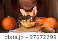 female chef slices pumpkin into a large glass bowl. 97672299