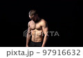 Muscular shirtless man playing with muscles, on black background. 97916632