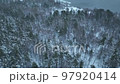 Flight over the autumn mountains with road serpentine and pine forest. Top down view. Landscape photography. Driving in winter. Natural winter landscape from air. Forest under snow a the winter time. 97920414