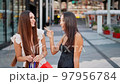 Multiethnic shopaholics talking and laughing on street 97956784