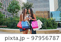 Multiracial shopaholics using smartphone on street 97956787