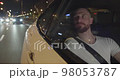 Male passenger is wearing a seat belt traveling by taxi in the night through the city 98053787