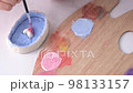 A child makes a craft for Valentine's Day. A close-up of the brush paints the heart pink. Gift. A pink heart on a blue background. 98133157