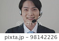 Young man wearing a suit wearing a headset and looking at the camera 98142226