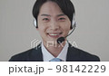 Young man wearing a suit wearing a headset and looking at the camera 98142229