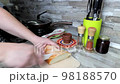 Cutting fresh bread into pieces in kitchen interior with a special knife 98188570