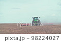 Modern red tractor plows an agricultural field 98224027