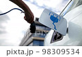 electric powered car in garage as man removes charging cable from vehicle electric car industry future drive modern 98309534