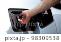CLOSE UP: Opening charging port and plugging electric cable in, recharging the battery Electrical car recharging 98309538