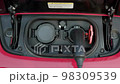 CLOSE UP: Opening charging port and plugging electric cable in, recharging the battery Electrical car recharging 98309539