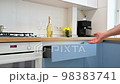 Man's hand closing a drawer at modern blue-teal and white kitchen 98383741