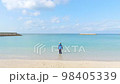 一個孩子在沙灘上穿鞋進入海水 98405339